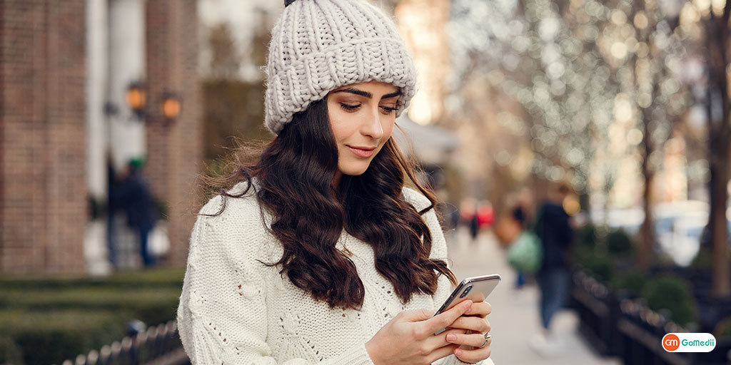 a girl wearing winter attire and looking at her phone