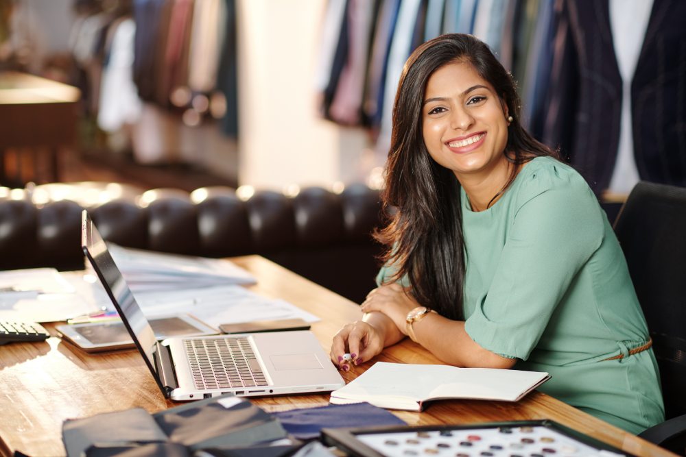 a direct saleswoman sitting on her work-table smiling