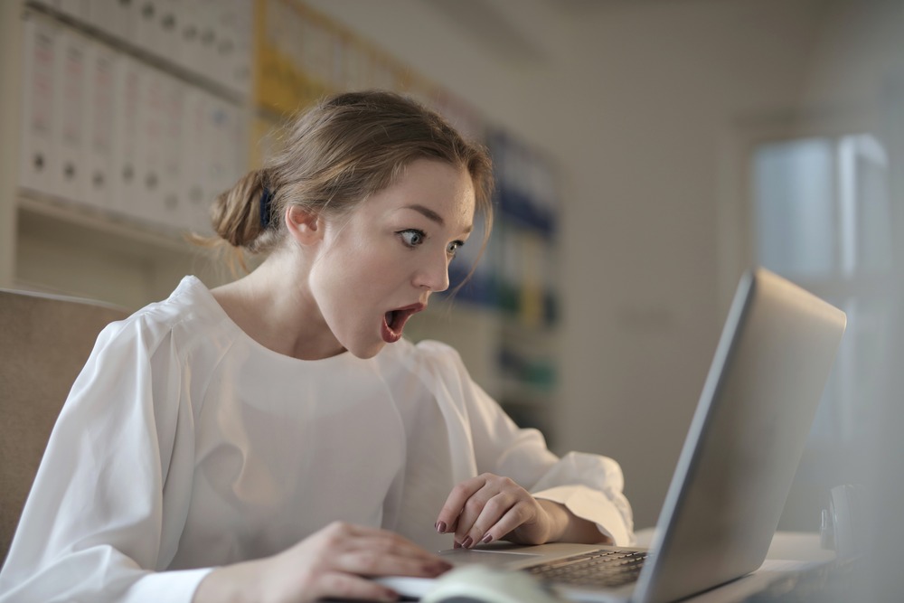 a woman looking shocked at her laptop