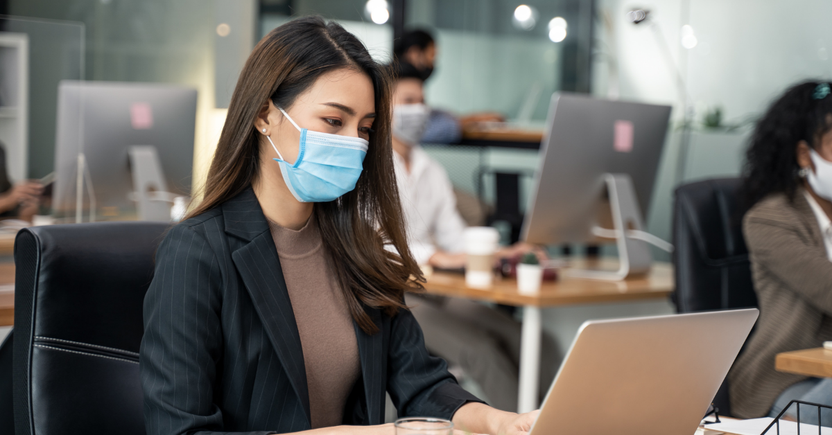 a woman wearing a face mask in her office and working